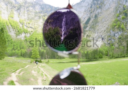 Creative view of a mountain waterfall through sunglasses lens, symbolizing travel, adventure, nature perspective, and inspiration outdoors.