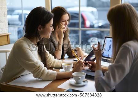 Creative web designers discussing ideas for site layout updating online store through rebranding campaign using laptop computer connected to free wireless internet in coffee shop during break