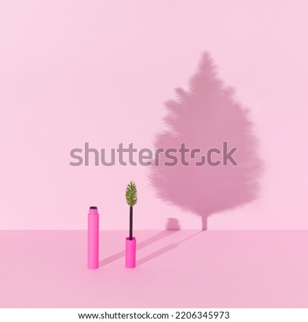Creative winter makeup composition made with pink mascara with Christmas three branch and Christmas tree shadow against bright pink background. Minimal New Year fashion beauty party concept. 