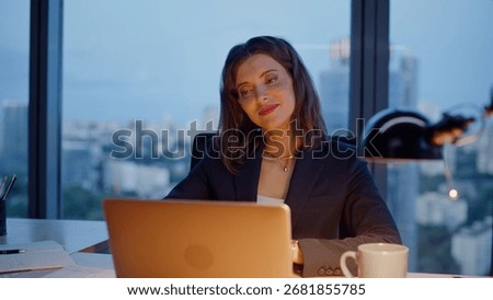 Creative worker looking laptop at evening office pondering marketing strategy closeup. Smiling woman manager working late thinking on career growth. Elegant businesswoman typing email at computer.