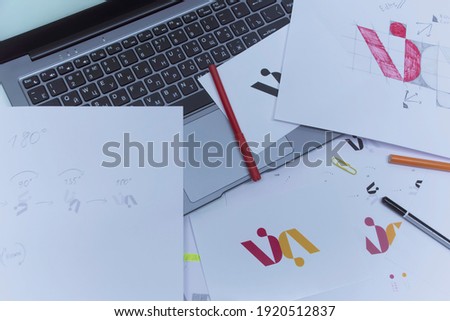 Creative workplace of a Graphic Designer. Development of a logo for the company. Drawings and sketches on paper in a art studio office