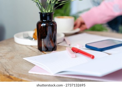 Creative Workspace in Cafe with Open Notebook and Red Pen