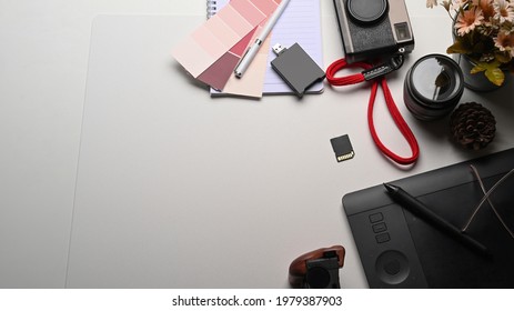 Creative workspace with digital tablet, camera and plant on white table.