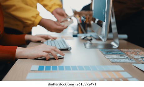 A creative workspace featuring a person using a computer mouse while color palettes and design materials are arranged neatly on the desk, showcasing a vibrant workspace. SACTR