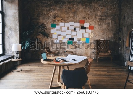 Creative workspace with papers, tech tools, and mood board on rustic wall represents visual strategy, agile project management and UI brainstorming environment.