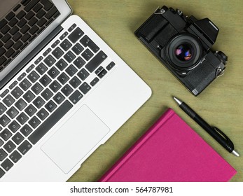 Creative Workstation Laptop Computer and 35mm Film Camera With a Pen and Notebook