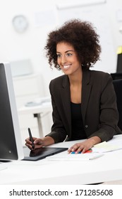 Creative Young Mixed Race Woman Smiling While Working As A Designer At Her Desk, On A Graphic Tablet In Front Of A Big Monitor