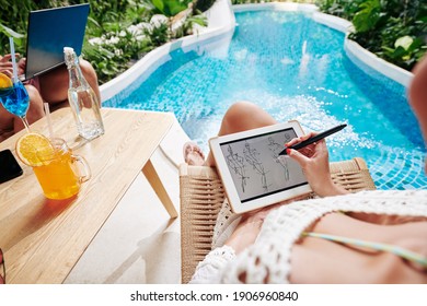 Creative young woman resting by swimming pool, drinking orange cocktail and drawing fashion sketch on tablet computer - Powered by Shutterstock