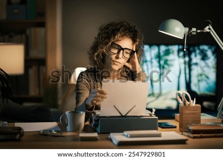 Creative young writer working in her home office, she is using a vintage typewriter and checking her work