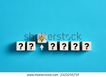 Creativity, brainstorming, problem solving and selecting the best idea for business development. Idea icon comes out of a row of question mark icons on wooden cubes.