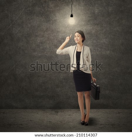 Creativity concept: beautiful asian businesswoman pointing a bright light bulb