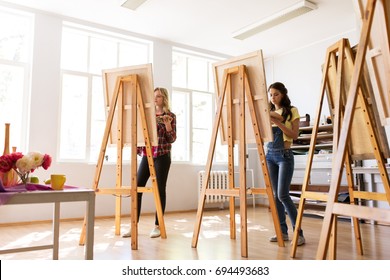 creativity, education and people concept - group of woman artists or students painting still life on easels at art school studio