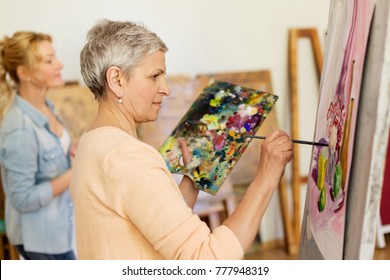 creativity, education and people concept - senior woman with brush and palette painting still life picture on easel at art school studio - Powered by Shutterstock