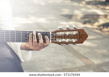 Creativity in focus. Young man in sun park holding a guitar and playing music