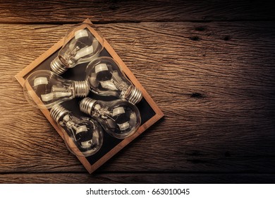 creativity ideas concept with light bulb on chalkboard on wooden texture background with free copyspace for your ideasd texts