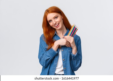 Creativity, Imagination And People Concept. Cheerful Good-looking Female College Student Painting, Likes Create Artworks, Holding Colored Pencils And Smiling, Tilting Head Dreamy, White Background