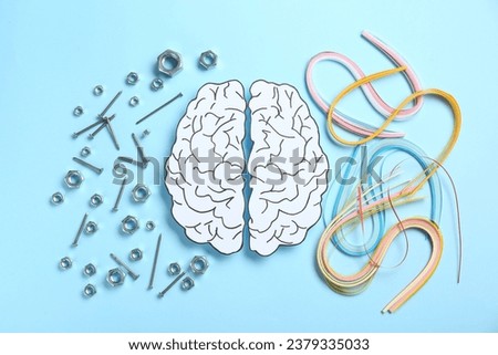 Creativity and logic. Paper brain on light blue background, flat lay. Screws with nuts near left hemisphere and quilling strips near right one