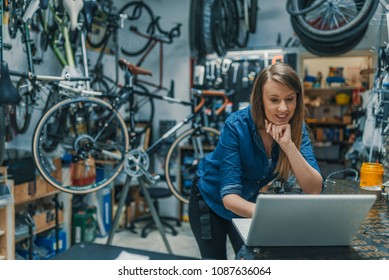 Creativity is a process. Woman mechanic working on a laptop. Female Bicycle Mechanic. Female mechanic in bicycle store. Young female mechanic with laptop - Powered by Shutterstock