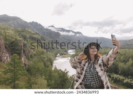 A creator of content for social networks, a young girl photographer shoots summer mountains in Khakassia. Freelance concept, travel, blogger, remote work