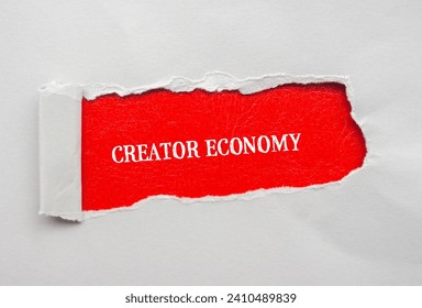 Creator economy lettering on ripped gray paper with red background. Conceptual business photo. Top view, copy space for text.