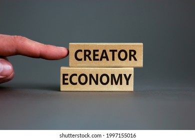 Creator economy symbol. Wooden blocks with words Creator economy on beautiful grey background, copy space. Businessman hand. Business and creator economy concept.