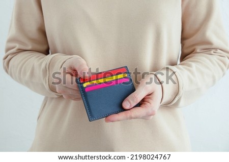 Credit bank cards in a gray business card holder in the hands of a caucasian woman. White background.