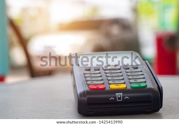 Credit card machine with car refueling petrol at\
gasoline station in background.\
Credit card reader payment, buy\
and sell products & service \
Credit Card Terminal or EDC on\
cashier table.