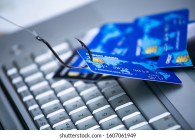 Credit card phishing. Piles of credit cards with a fish hook on computer keyboard. Credit card phishing scam with credit card in fishing hook