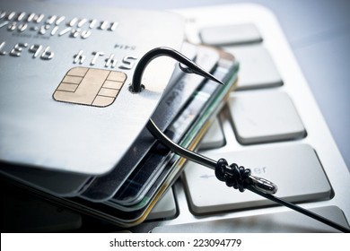 credit card phishing - piles of credit cards with a fish hook on computer keyboard - Shutterstock ID 223094779