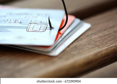 Credit card phishing scam with credit card in fishing hook on wooden table