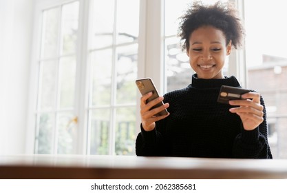 Credit Card In The Phone. A Beautiful Woman Smiles Writes To The Bank Payment Online.  Work At Home Online. The Hostess Keeps Records On The Internet.