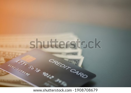 The credit card is placed on top of the dollar bill. All are placed on the table, close-up view.Concept spending money.