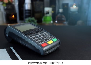 credit card reader pos machine and a credit card are on the wooden black table with background in the home aromatic fragrance products retail shop