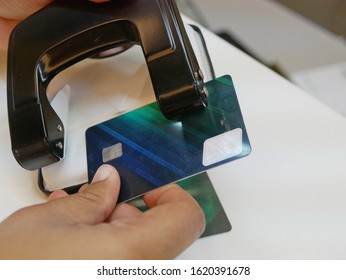 A Credit Card In A Woman's Hands Being Cut / Punched By A Hole Puncher - Breaking Free Of Financial Bondage