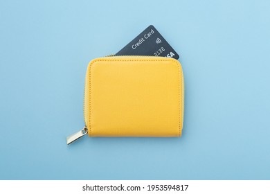 Tarjeta de crédito en cartera amarilla en fondo azul, vista superior
