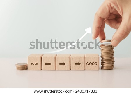 For credit score concept, poor to good text with arrow icon on wooden cube block with hand arranged stack of coin including copy space
