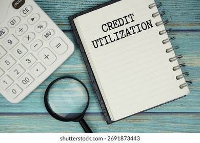 Credit Utilization text on notepad with magnifying glass and calculator on wooden background