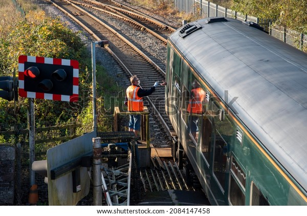 Crediton, Devon, England, UK.\
2021. Signalman presents a key to the train driver at Crediton\
station. The key gives the train driver access onto a single track\
line.
