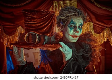 A creepy clown in a stage costume greets the spectator  in an old circus and smiles widely. Halloween. Horror, thriller.