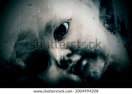 Creepy doll face behind the old glass