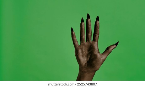 Creepy halloween devil monster hand in black paint with nails shows open palm, isolated on chroma key green screen background, workspace mockup. - Powered by Shutterstock