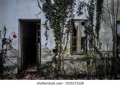 Creepy Haunted House Facade With Broken Window, Open Door And Bloody Hand On The Wall. Scary Front View Of An Old Abandoned House With Dark Horror Atmosphere And Trace Of Blood Like In Horror Movies.