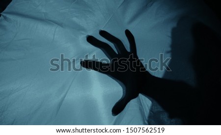 Creepy night scene: A woman's silhouette behind the fabric, a hand suddenly hits the fabric, causing terror and fear