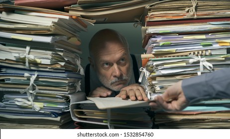 Creepy office clerk overloaded with paperwork, he is peeking out from a hole