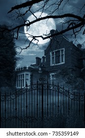 Creepy Old House At Night With Iron Gates, Trees And A Large Moon