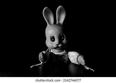 Creepy Rabbit With Glowing Eyes. A Scary Toy Rabbit Is Sitting At The Table