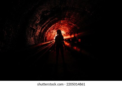Creepy silhouette in the dark underground sewer tunnel. Horror about maniac concept