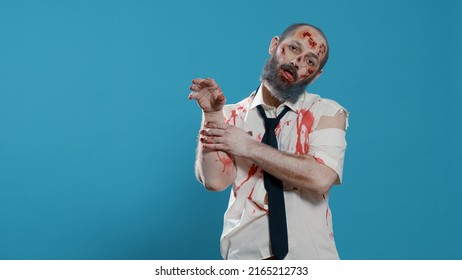 Creepy Zombie With Deep And Bloody Scars Standing On Blue Background. Mindless Looking Brain Dead Crazy Monster Acting Bizarre While Growling Sinister And Spooky At Camera. Studio Shot