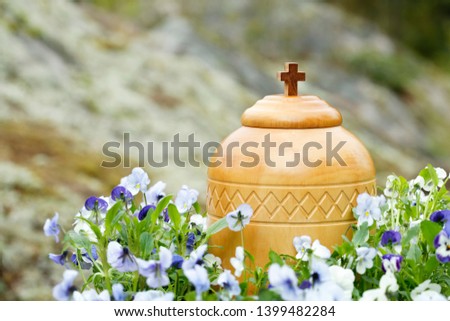 cremation urn surrounded by blue violets ready for spreading the ashes in nature