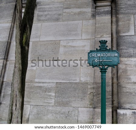 Crematorium. Inscription on a metal panel. Cemetery path.